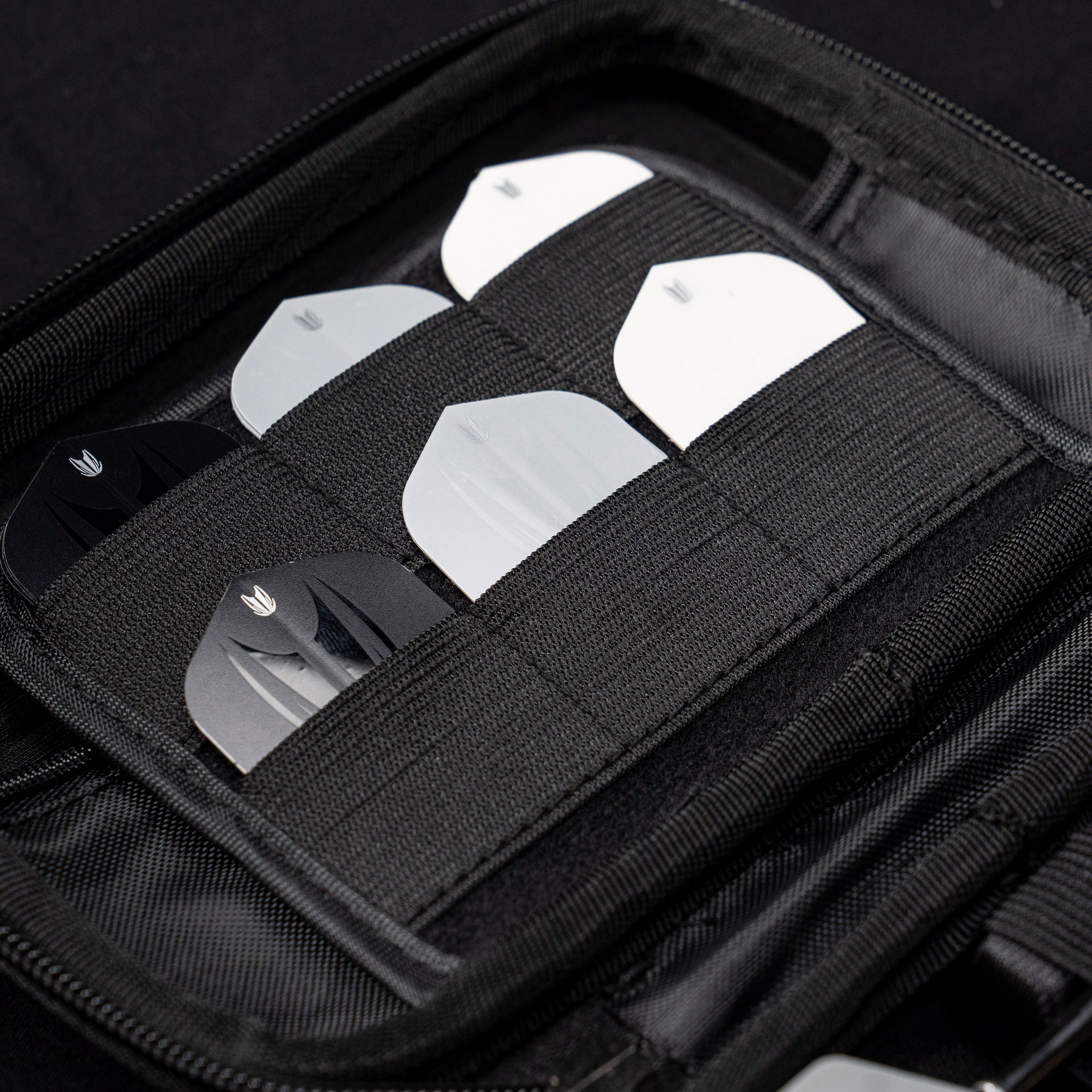 Takoma Ghost Series Stephen Bunting dart case Das Bild zeigt das Target Takoma Bolide Dartcase, in dem mehrere Dart-Flights ordentlich in elastischen Halterungen verstaut sind. Das Case ist schwarz und bietet sicheren Schutz für das Dartzubehör.