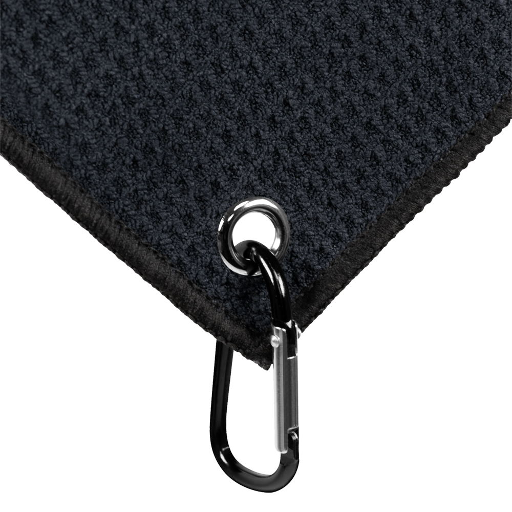 JD7032_Mission_Jack_Daniels_Handtuch_3 Das Bild zeigt eine Ecke eines schwarzen Handtuchs mit einer Öse und einem Karabinerhaken. Das Produkt heißt "Mission Jack Daniels Handtuch".