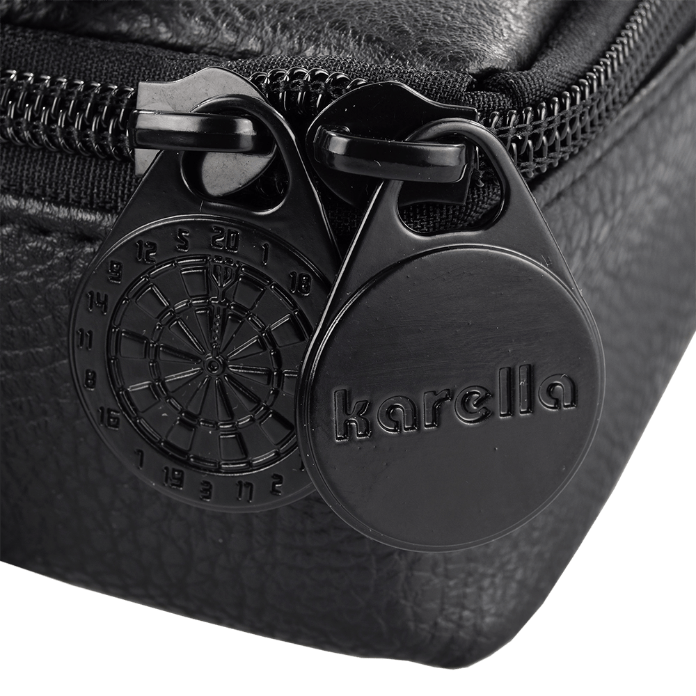 Pak5_Master_Pak_Leder_Edition_Darttasche_3 Das Bild zeigt einen Detailausschnitt der "Master Pak Leder Edition Darttasche". Zu sehen sind zwei schwarze Reißverschluss-Anhänger, einer davon mit einer Dartbord-Gravur und der andere mit dem Schriftzug "karella".