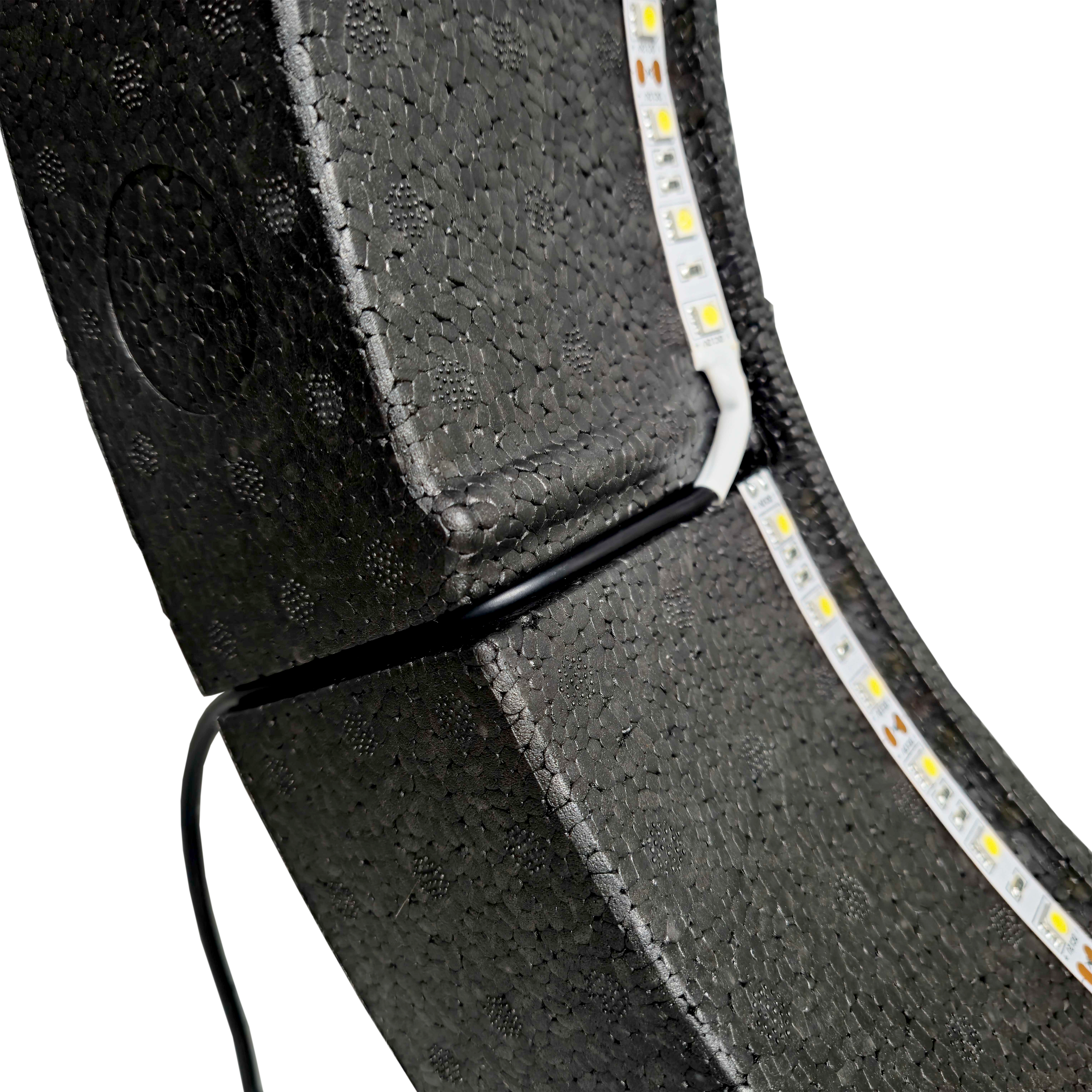 Bulls NL Lumo Light Surround lighting system Das Bild zeigt das „Bulls NL Lumo Light Surround Beleuchtungssystem“ mit LED-Leuchtstreifen auf einer schwarzen, strukturierten Oberfläche. Ein Kabel ist ebenfalls an das Beleuchtungssystem angeschlossen.