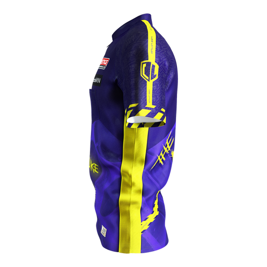 Target Coolplay Luke Littler 2025 dart shirt Das Bild zeigt ein Dartshirt in lila und gelb mit auffälligem Design. Auf dem Ärmel steht "LUKE LITTLER" und es sind verschiedene grafische Elemente abgebildet.