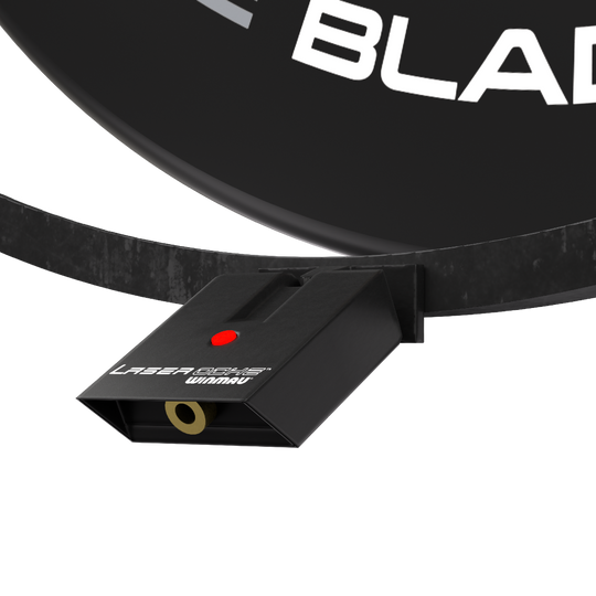 Winmau Plasma Accessory Set Das Bild zeigt das Winmau Plasma Zubehör Set, das an einem Dartboard befestigt ist. Sichtbar ist ein schwarzes Gerät mit der Aufschrift "Laser Oche Winmau" und einem roten Knopf.