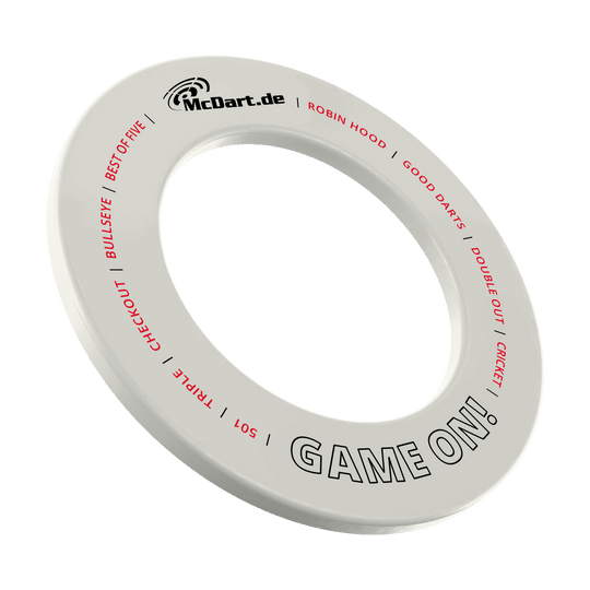 Das Bild zeigt einen weißen Dartboard-Surround-Ring mit der Aufschrift "McDart.de" und "GAME ON!". Auf dem Ring stehen außerdem in roter Schrift Begriffe rund um das Dartspiel wie "BULLSEYE", "TRIPLE", "CHECKOUT" und "CRICKET".