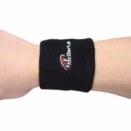 1690_2 Auf dem Bild ist ein schwarzes Schweißband mit der Aufschrift "McDart" zu sehen. Das Schweißband wird am Handgelenk getragen.
